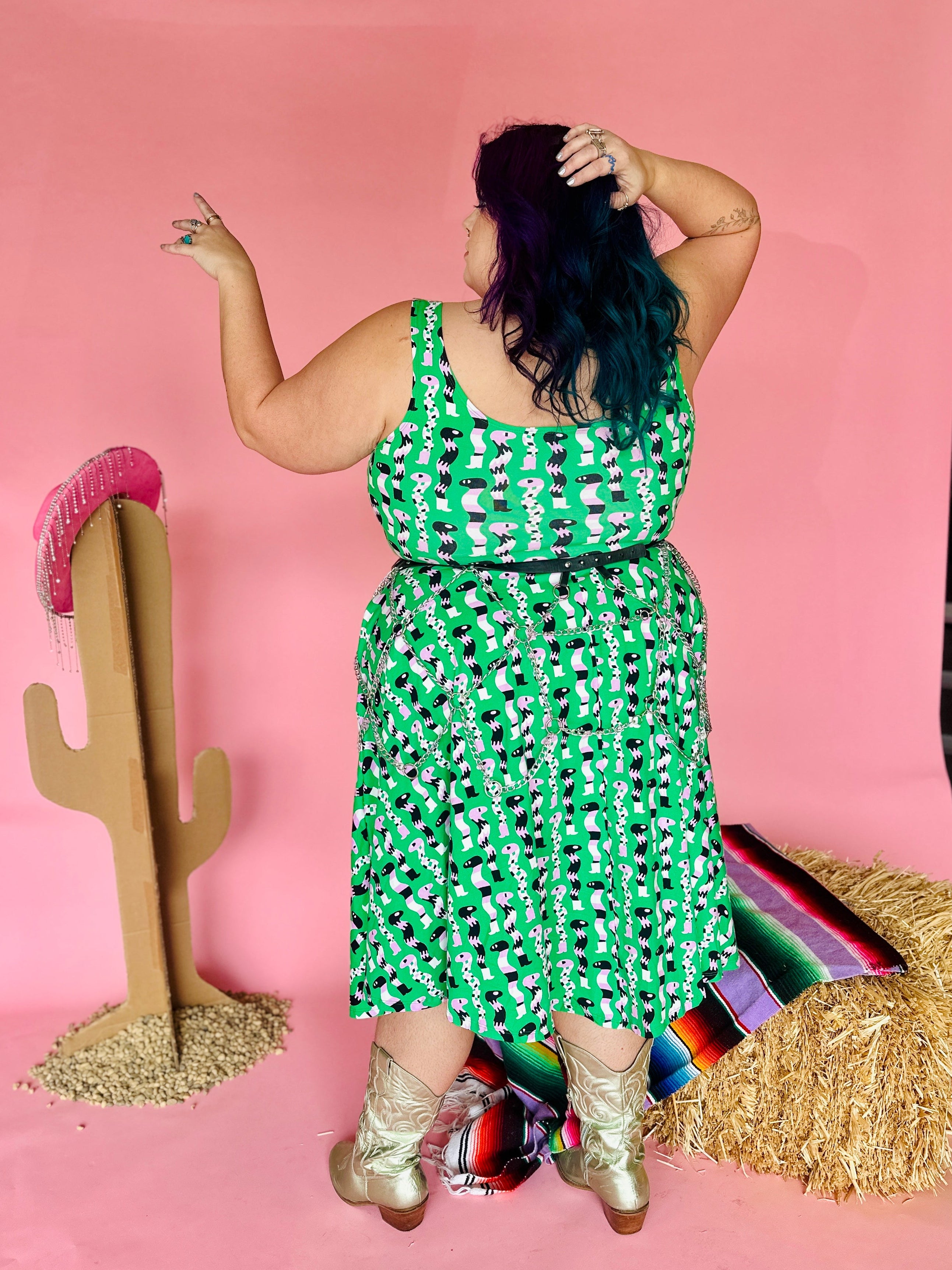 Person wearing a green patterned dress with a pink background and cactus decoration.